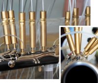 Робот в целом состоит из двух частей. Есть часть с манипуляторами, которые управляют клапанами, — это все медные трубки. А за ними видна такая штука, набитая чем-то белым, — так вот это камера воздушного давления, в которую помещен мундштук кларнета. Она действует как рот музыканта