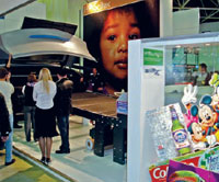 В момент открытия кожуха HP Scitex TJ8300 принтер немедленно окружала толпа любопытствующих — мало кто мог избежать соблазна попробовать пересчитать все 150 печатающих головок. Справа— витрина с образцами печати на планшетном FB6700 