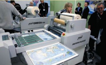 Оба ламинатора профессиональные полуавтоматические. GMP Protopic-Plus 520 (на переднем плане) формата 520в720мм оснащён эмбоссирующим валом. Скорость до 15 м/мин. GMP Omega-720 работает с большим форматом — до 720в1020мм со скоростью до 20 м/мин. Механизм автопротяжки листов включает шторку для автоматического нахлёста. Для модели также возможна замена основного вала на эмбоссирующий