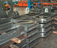 Подготовленные к монтажу после чистовой фрезерной и токарной обработки боковые станины флексографской машины Diamond HP. На заднем плане в верхнем углу слева — готовая к монтажу и покраске собранная станина устройства размотки 