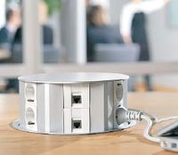 Рисунок 8. Самовыдвижной круглый блок  в системе OptiLine 45, разработанный компанией Schneider Electric, рассчитан на 12 модулей 45х45 мм. Он врезается в столешницу и автоматически поднимается при нажатии на него.