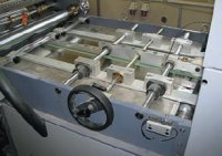 Боковые упоры приёмного стола клеевого модуля регулируются вручную червячной парой, а лист движется по центральному ленточному транспортёру сшариковыми прижимами